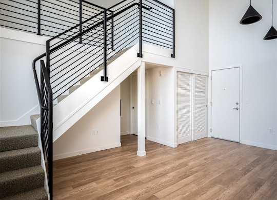 a living room with a staircase in a house with white walls and wood floors