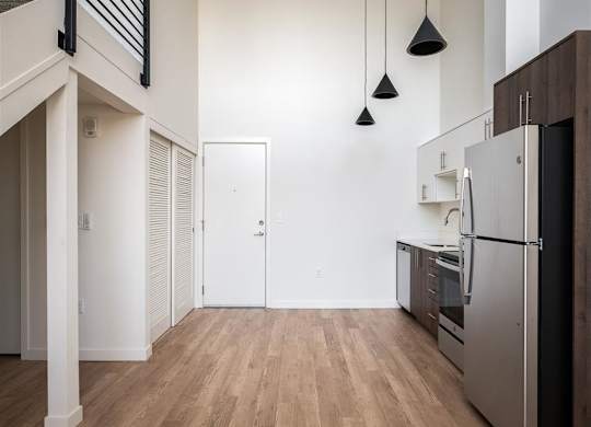 a renovated kitchen with white walls and wood floors and a stainless steel refrigerator
