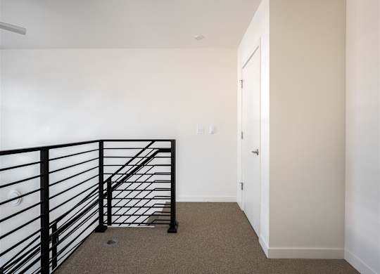 a stairwell in a home with a black railing and white walls