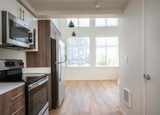 an empty kitchen and living room with a stove refrigerator and microwave