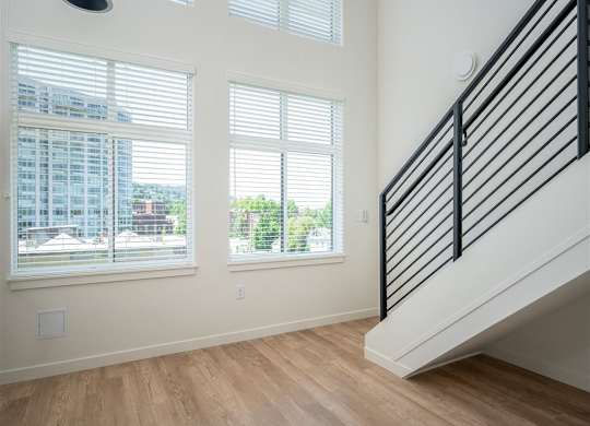 a living room with three windows and a staircase