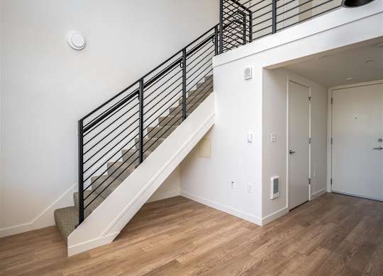 a view of a stairwell in a home with white walls and wood floors