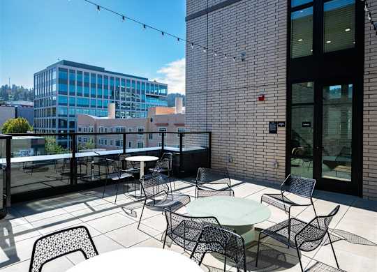 a rooftop patio with tables and chairs and a city in the background