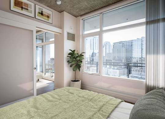 a bedroom with a bed and a large window and a plant