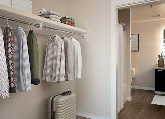 a closet with clothes hanging on a rack and a suitcase