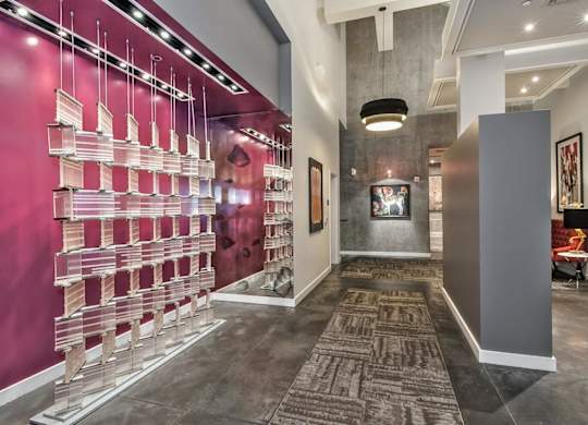 a long hallway with a pink wall and a glass case with pink and white bottles