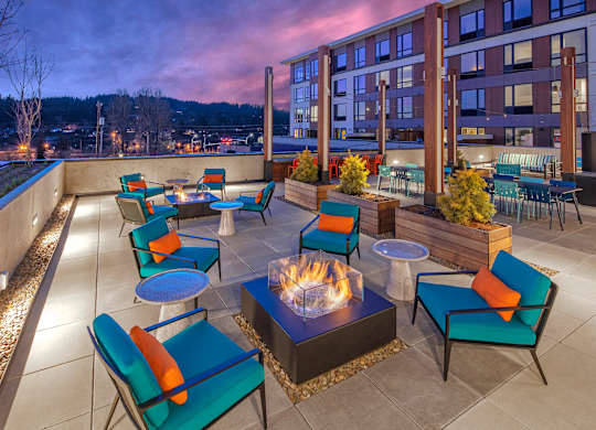 A patio with a fire pit and chairs.