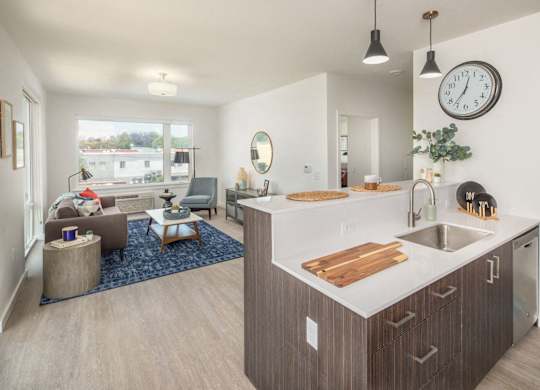 A modern kitchen with a large island and a living room with a couch and a chair.