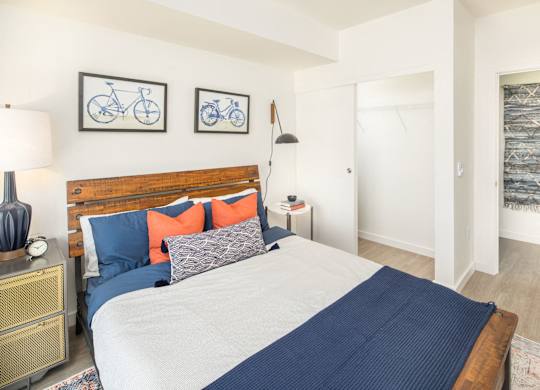A bedroom with a bed, nightstand, and two bicycle pictures on the wall.