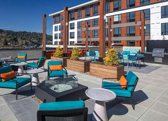 A patio with blue chairs and a table with a glass top.