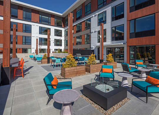 A patio with blue chairs and a fire pit.
