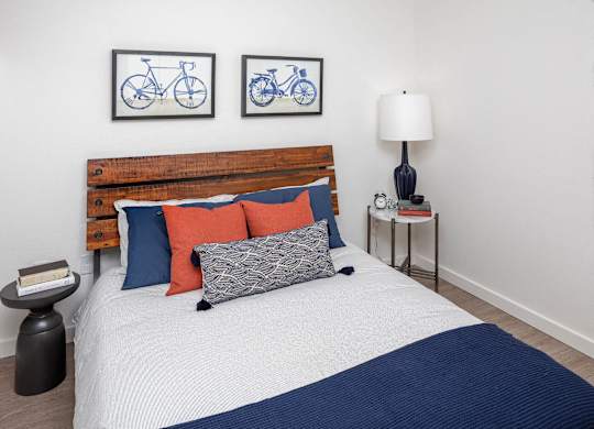 A bed with a wooden headboard and a white comforter with a blue blanket on it.