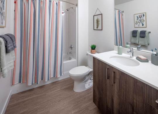 A bathroom with a toilet, sink, and striped shower curtain.