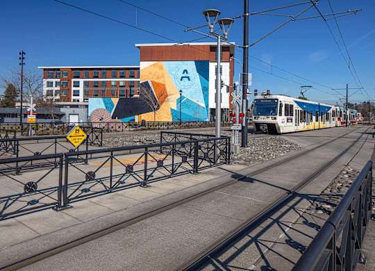 A train is on the tracks in front of a colorful building.
