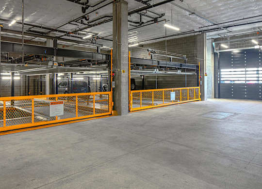 A large, empty warehouse with orange safety barriers.