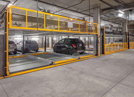 A black car is parked in a yellow and grey parking garage.