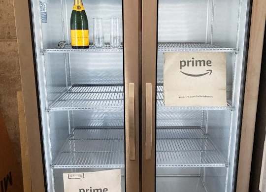 Two refrigerators, one with a bottle of champagne and one with a Prime bag.