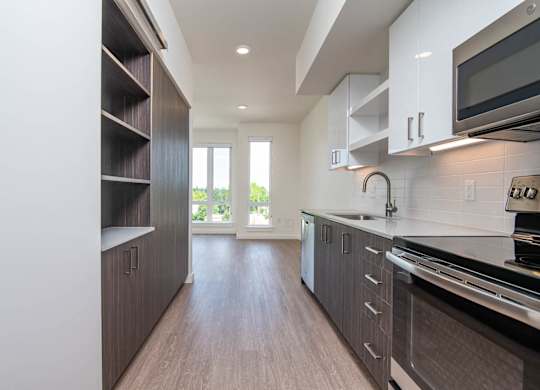 A modern kitchen with dark wood floors and stainless steel appliances.