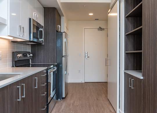 A kitchen with dark wood cabinets and a white counter top.