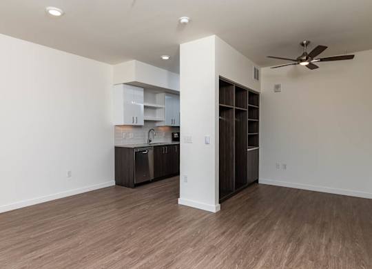 A room with a ceiling fan and a kitchenette.