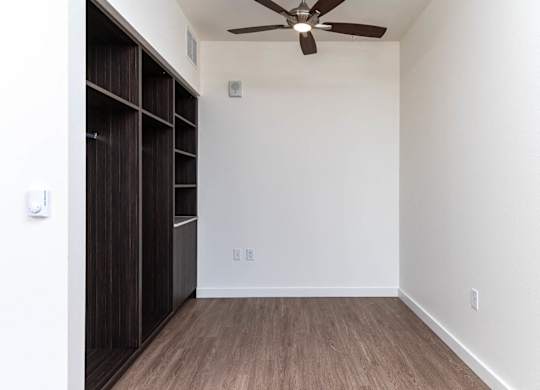 A room with a ceiling fan and wooden flooring.