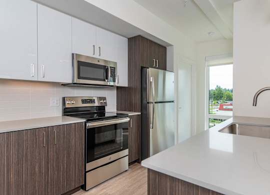 A modern kitchen with a white countertop and stainless steel appliances.