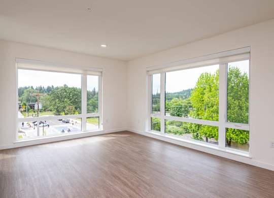 A large empty room with a view of a street and trees outside.