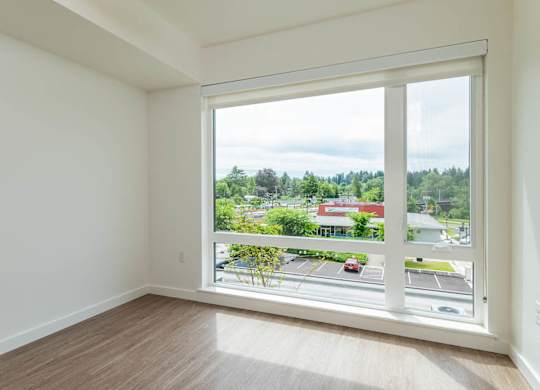 A room with a large window overlooking a parking lot and buildings.