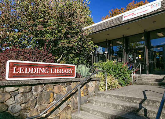 The Ledding Library is a beautiful building with a stone wall and steps leading up to the entrance.