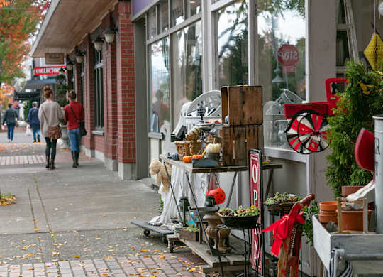 A street scene with a woman walking past a storefront with a sign that says