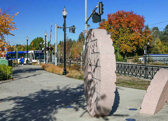 A large stone sculpture is in the foreground of a city street.