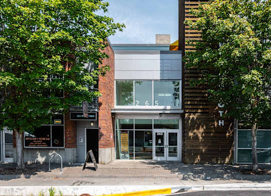 a brick building with glass windows and a tree on the sidewalk