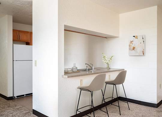 a small kitchen with a counter and two stools