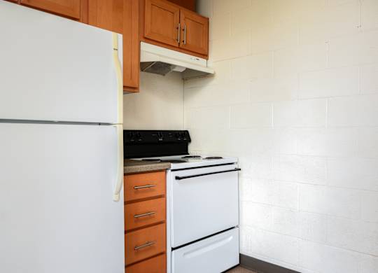 an empty kitchen with a white refrigerator and stove