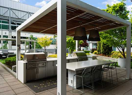 A white outdoor kitchen with a grill and table.