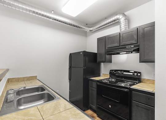 A kitchen with black appliances and a stainless steel sink.