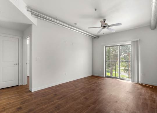 A room with a ceiling fan and sliding glass doors.