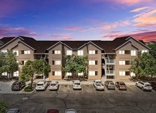 A large apartment complex with a parking lot in front.