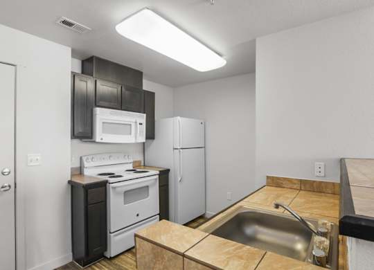 A kitchen with a stove, oven, refrigerator, and sink.