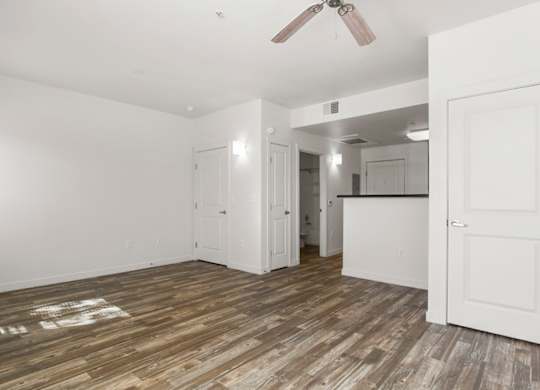 A room with a ceiling fan and wooden flooring.