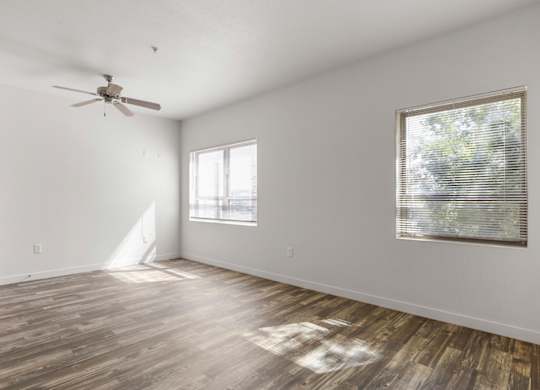A room with a ceiling fan and a window with blinds.