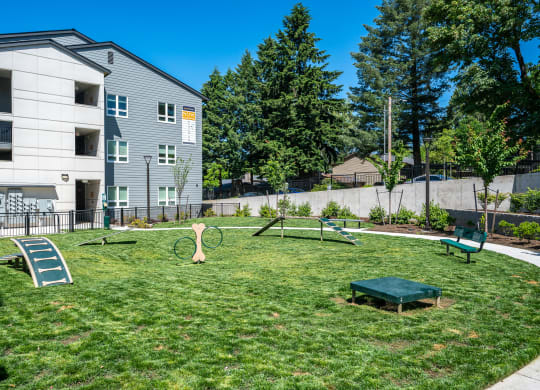 a yard with a swing set and a bench in front of a building