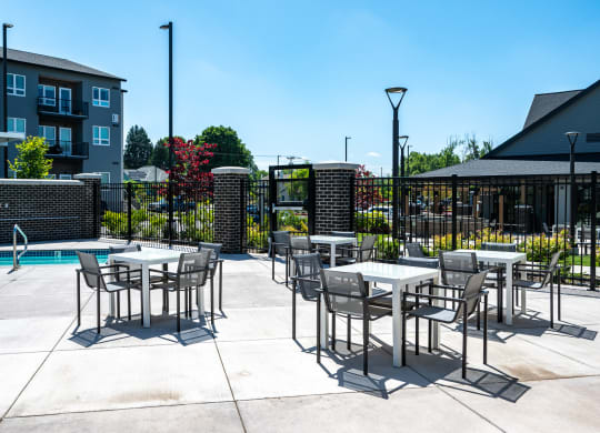an outdoor patio with tables and chairs next to a swimming pool