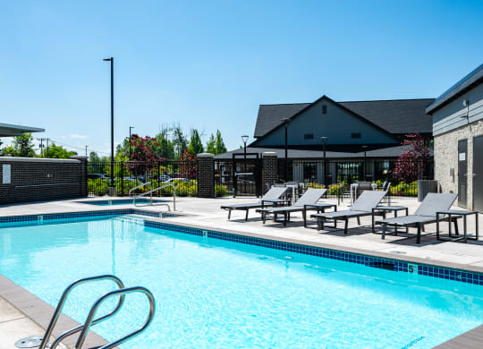 a swimming pool with chairs and a building in the background