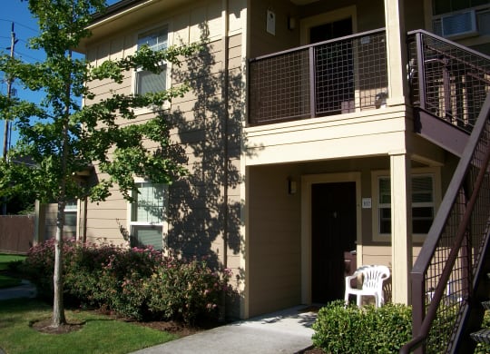 an exterior view of a building with a porch and a chair on the sidewalk
