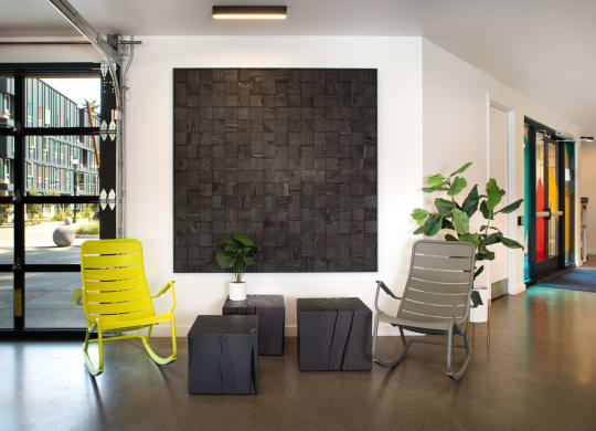 a black brick wall in the middle of a room with two yellow chairs in front of it