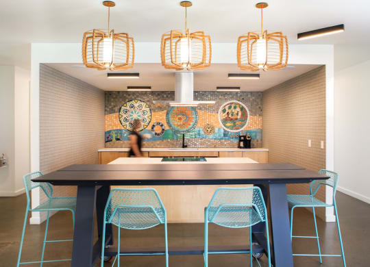 a large table with blue chairs in front of a mosaic wall