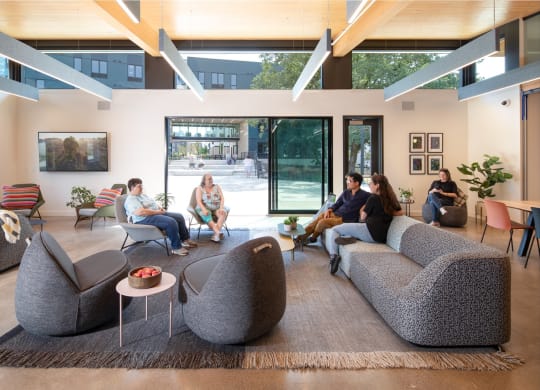 people sitting in a living room with couches and chairs