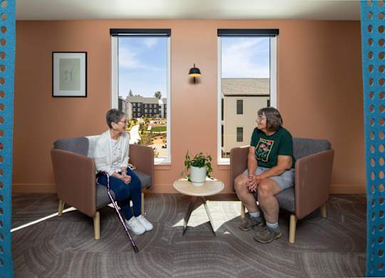 Two people sitting in a room with orange walls.