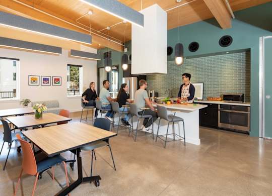 A group of people are sitting around a table in a modern kitchen.